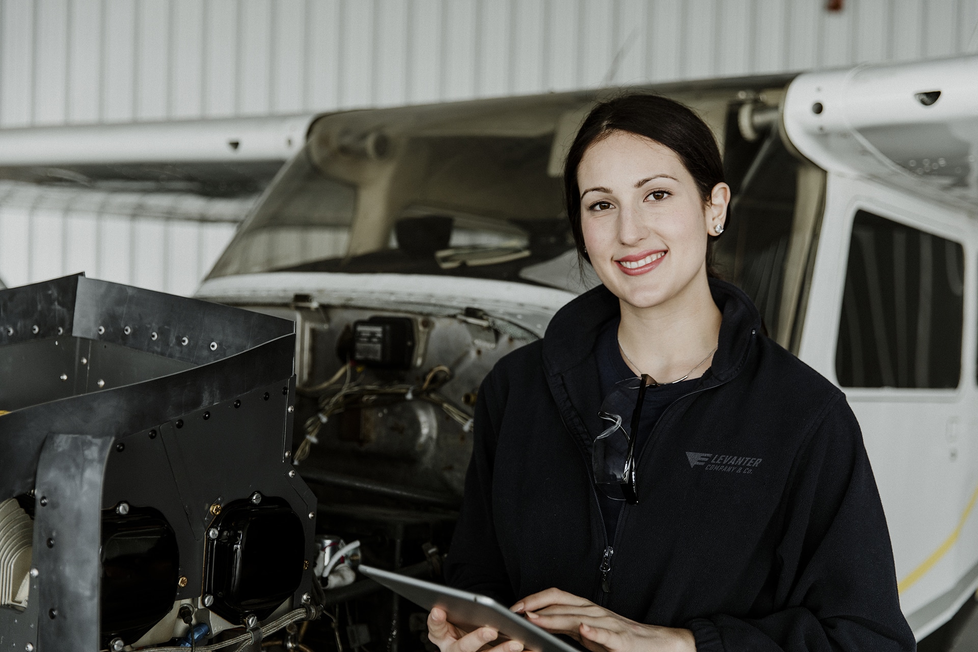 Female aviation technician repairing the motor of a propeller plane