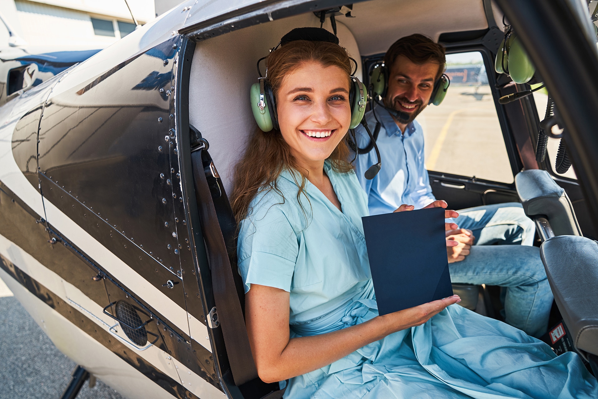 Joyful woman and aviation tutor posing for camera in chopper